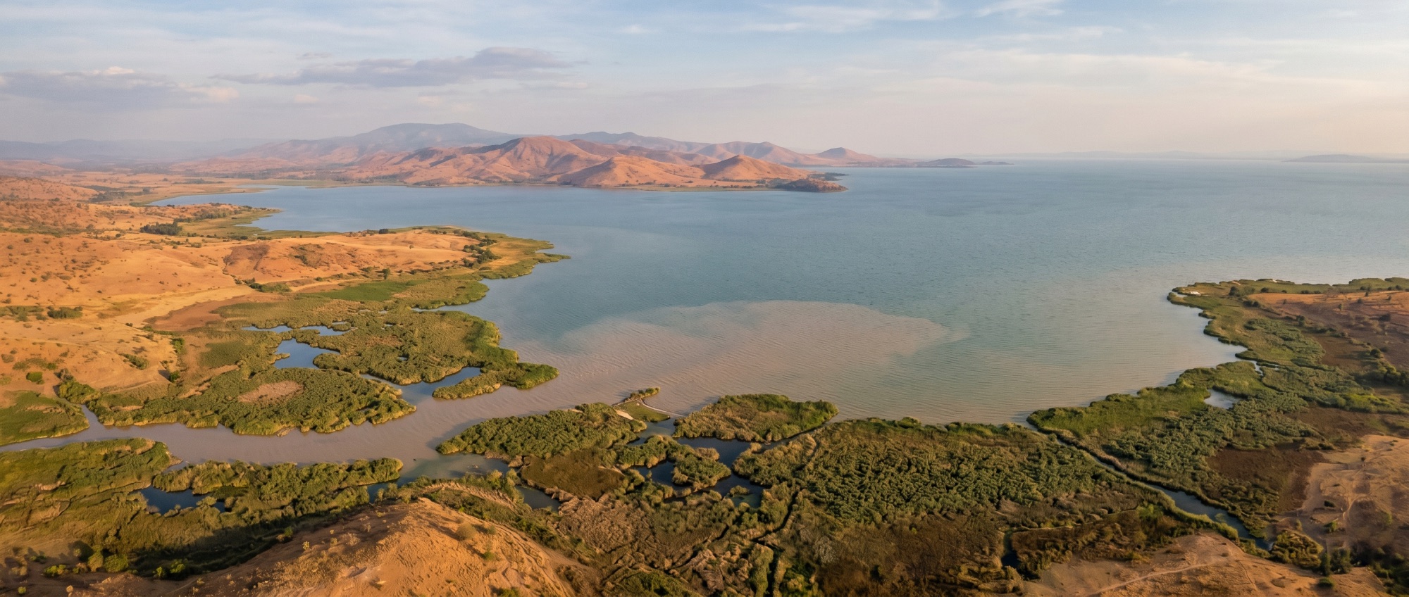Wide aerial panorama of the southern basin of Lake Victoria — wetlands, river deltas and sediment meeting open water